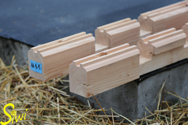 Die ersten Holzbalken werden auf der Bodenplatte aufgelegt.